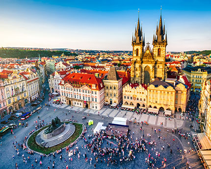 Historic Old Town Square in Prague, Czech Republic, featuring colorful Baroque buildings, the Church of Our Lady before Týn, and lively cafés.